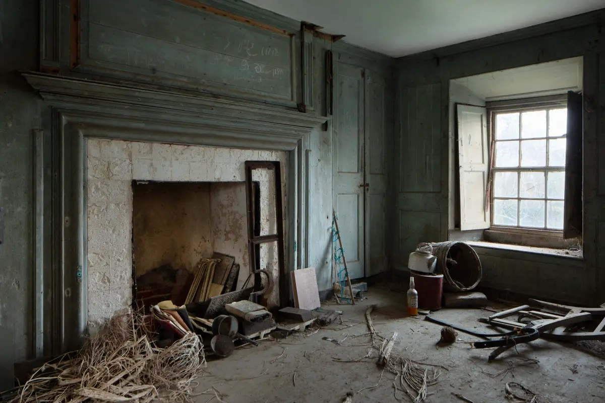 A panelled parlour with a wide stone fireplace, initials and the dates 1911 and 1912 pencilled on the overmantel
